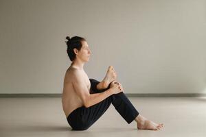 a man with a naked torso does yoga in the gym. the concept of a healthy lifestyle photo