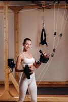 A girl in a sports uniform put devices on her hands for mounting on a simulator where she will do body stretching photo