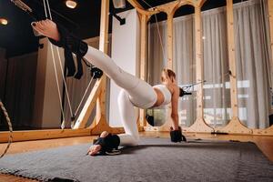 A girl in a sports uniform does exercises on a simulator for stretching the human body photo