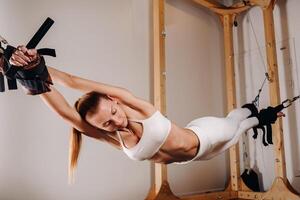 A girl in a sports uniform does exercises on a simulator for stretching the human body photo