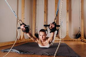 A girl in a sports uniform does exercises on a simulator for stretching the human body photo