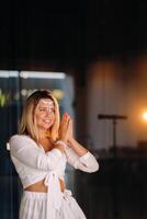 Portrait of a smiling girl in a white dress with her palms clasped in front of her photo