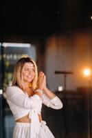 Portrait of a smiling girl in a white dress with her palms clasped in front of her photo