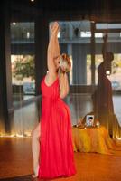 A girl in a red dress moves in a dance meditating indoors . Dynamic dance photo