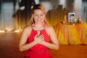 Meditation and concentration. a woman in a red dress, sitting on the floor with her eyes closed, is practicing medicine indoors. Peace and relaxation photo