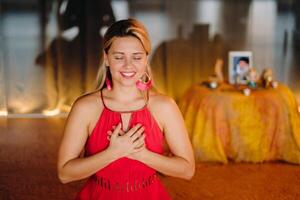 Meditation and concentration. a woman in a red dress, sitting on the floor with her eyes closed, is practicing medicine indoors. Peace and relaxation photo