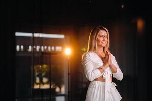 Portrait of a smiling girl in a white dress with her palms clasped in front of her photo