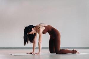 a woman in a brown suit does yoga in a fitness room . Healthy lifestyle, fitness, training, self-care photo