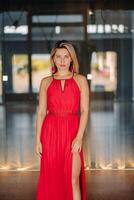 A girl in a red dress moves in a dance meditating indoors . Dynamic dance photo