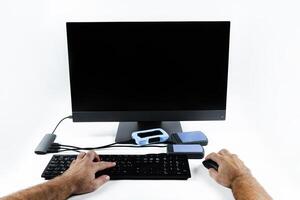 a person works on a computer by pressing the keyboard and holding a mouse on a white background.Monoblock with external hard drives photo