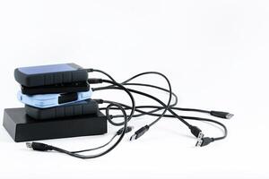 many external hard drives with wires lie on a white background. Hard drives on isolate. photo