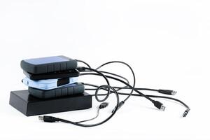 many external hard drives with wires lie on a white background. Hard drives on isolate. photo