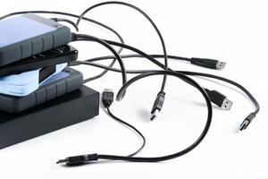 many external hard drives with wires lie on a white background. Hard drives on isolate. photo