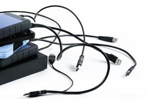 many external hard drives with wires lie on a white background. Hard drives on isolate. photo