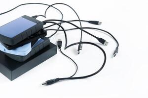 many external hard drives with wires lie on a white background. Hard drives on isolate. photo