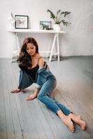 brunette with long hair poses in the studio sitting on the floor photo