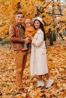 Father and mother with son walking in the autumn Park. A family walks in the Golden autumn in a nature Park. photo