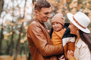 Father and mother with son walking in the autumn Park. A family walks in the Golden autumn in a nature Park. photo
