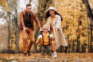 Father and mother with son walking in the autumn Park. A family walks in the Golden autumn in a nature Park. photo