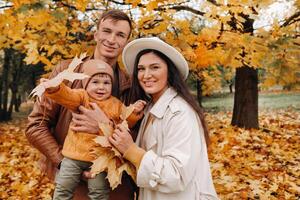 Father and mother with son walking in the autumn Park. A family walks in the Golden autumn in a nature Park. photo