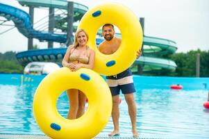 a man and a woman in a rubber inflatable circle stand against the background of a summer water park pool photo