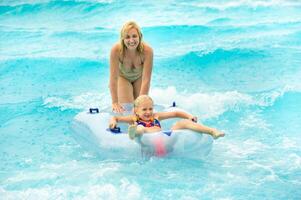 a woman with a child in a rubber inflatable circle plays in the pool of a summer water park in the rain photo