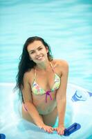 a woman in a bikini with a rubber inflatable circle playing and having a good time in the amusement park pool in the summer photo
