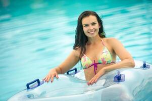 a woman in a bikini with a rubber inflatable circle playing and having a good time in the amusement park pool in the summer photo