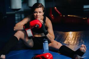 portrait of a female boxer in red gloves in the gym after training photo
