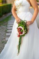 an unusual elongated wedding bouquet in the hands of the bride photo