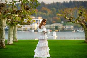 A bride in a white wedding dress in a park in an Austrian town with large trees at sunset photo