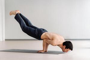 A man with a bare torso trains lying down, doing stretching in the gym photo