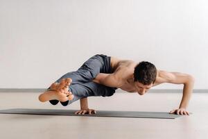A man with a bony torso trains lying down, doing a handstand in the gym photo