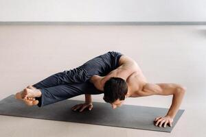 A man with a bony torso trains lying down, doing a handstand in the gym photo