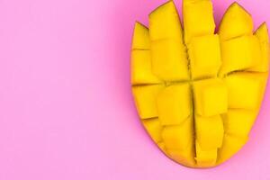 Fresh ripe mango on a pink background. Half a sliced mango on a pink background photo