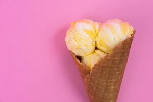 Fruit-scented ice cream balls in a waffle cone on a pink background. photo