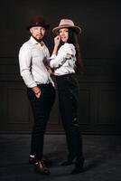 A man and a woman in white shirts and hats on a black background.A couple in love poses in the interior of the studio photo