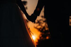 The concept of love and Valentine's Day. Close-up of the hands of a couple holding hands during sunset photo
