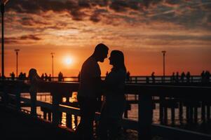 Portrait silhouette of a beautiful newlywed couple. A loving man hugs a girl at sunset, against the background of the sea standing on the pier. photo
