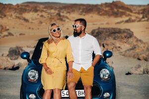 a woman and a man wearing glasses in a convertible car on a trip to the island of Tenerife. The crater of the Teide volcano, Canary Islands,Spain photo