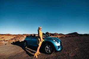 Woman enjoying road trip, standing with map near convertible car on the roadside in the volcanic mountain forest on Tenerife island, Spain. photo