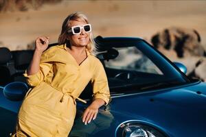 A life Portrait of a young woman enjoying a ride through a deserted valley, getting out of a convertible on the side of the road.Canary islands.Tenerife photo