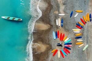 a beautiful couple is lying on the beach of France next to surfboards, shooting from a quadcopter, a lot of surfboards are unusually lying on the beach photo