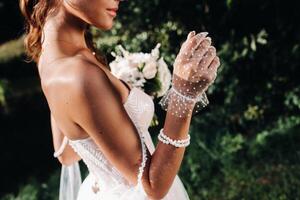 portrait of an elegant bride in a white dress with a bouquet in nature in a nature Park.Model in a wedding dress and gloves and with a bouquet .Belarus photo