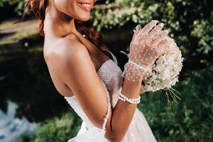 portrait of an elegant bride in a white dress with a bouquet in nature in a nature Park.Model in a wedding dress and gloves and with a bouquet .Belarus photo