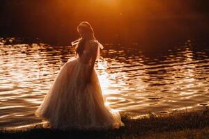 An elegant bride in a white dress enjoys nature at sunset.Model in a wedding dress in nature in the Park.Belarus photo