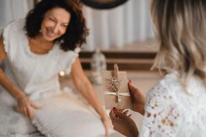 A woman in white clothes passes an envelope with a wish to another woman. The concept of the women's circle photo