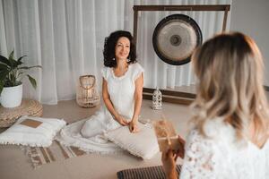 A woman in white clothes passes an envelope with a wish to another woman. The concept of the women's circle photo