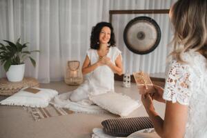 A woman in white clothes passes an envelope with a wish to another woman. The concept of the women's circle photo