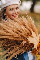 Portrait of a Girl in a jacket and birette with an autumn bouquet in an autumn park photo
